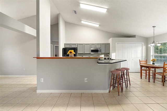 kitchen featuring decorative light fixtures, vaulted ceiling, gray cabinets, and black fridge with ice dispenser