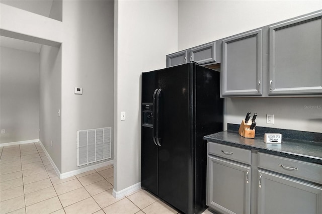 kitchen featuring gray cabinets, black fridge with ice dispenser, and light tile patterned floors