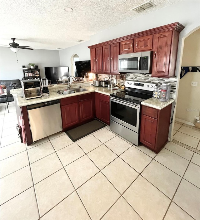 kitchen with light tile patterned floors, appliances with stainless steel finishes, kitchen peninsula, and sink