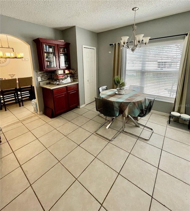 dining area featuring a textured ceiling, light tile patterned floors, and a notable chandelier