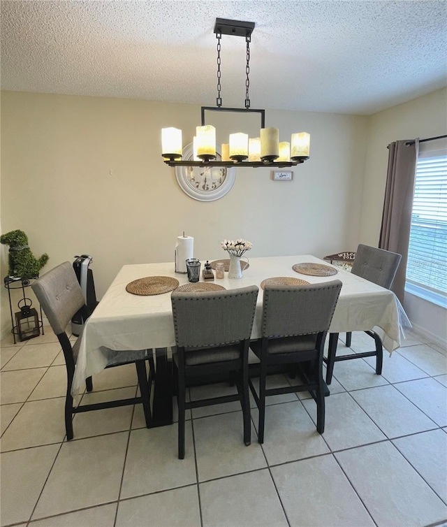 dining area featuring a textured ceiling, light tile patterned floors, and a chandelier