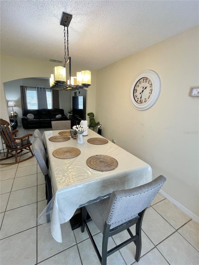 tiled dining space featuring a textured ceiling and an inviting chandelier