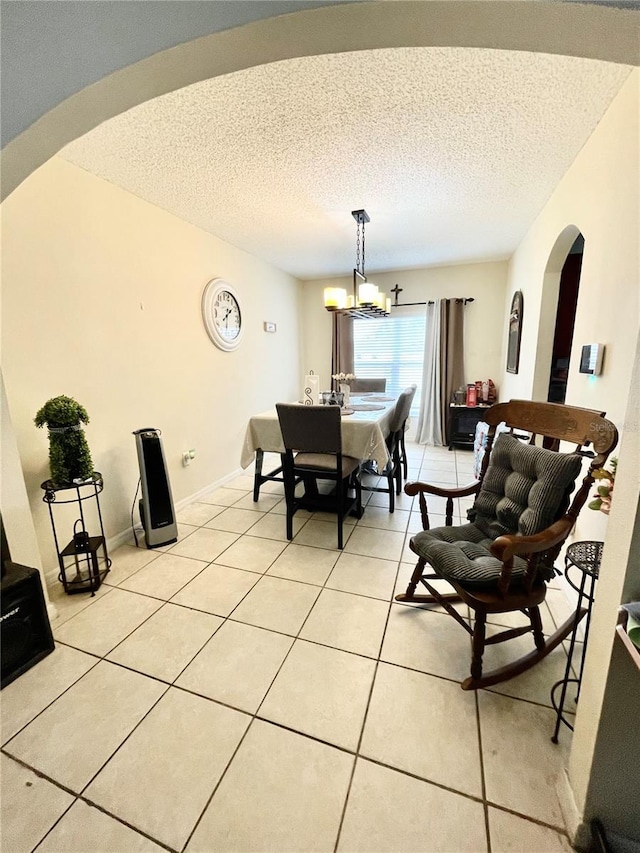 dining space featuring a textured ceiling, a notable chandelier, and light tile patterned flooring