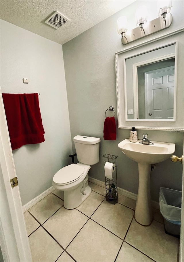 bathroom with toilet, tile patterned flooring, and a textured ceiling