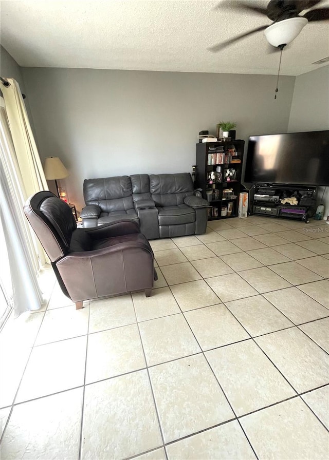 living room with ceiling fan, a textured ceiling, and light tile patterned floors