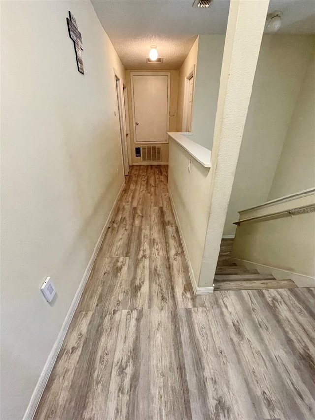 corridor featuring a textured ceiling and light hardwood / wood-style flooring