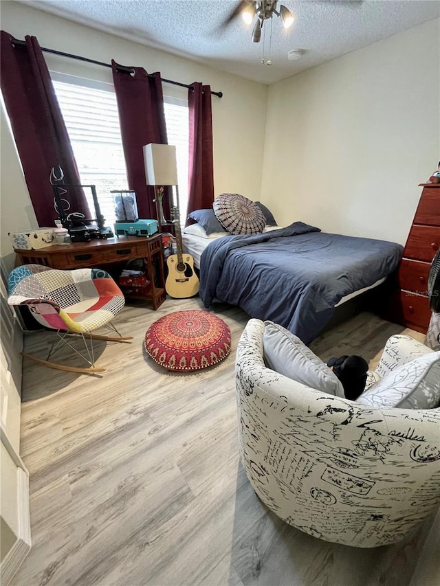 bedroom with ceiling fan, hardwood / wood-style floors, and a textured ceiling