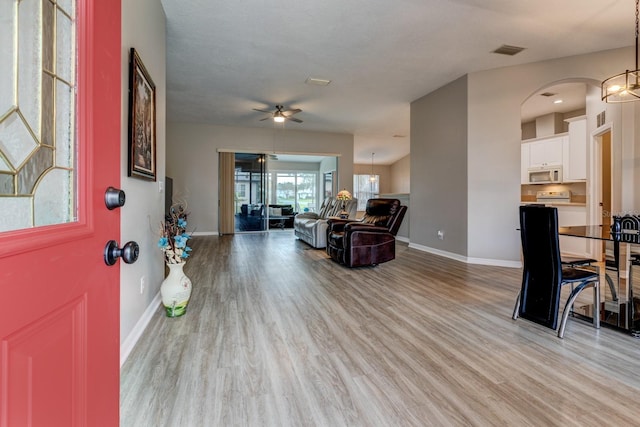 foyer with light hardwood / wood-style floors and ceiling fan with notable chandelier