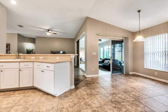 kitchen featuring vaulted ceiling, ceiling fan, hanging light fixtures, sink, and white cabinets