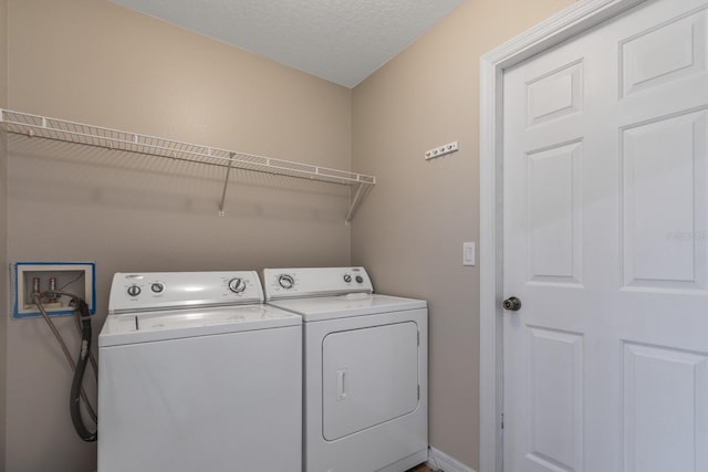 clothes washing area with a textured ceiling and washer and clothes dryer