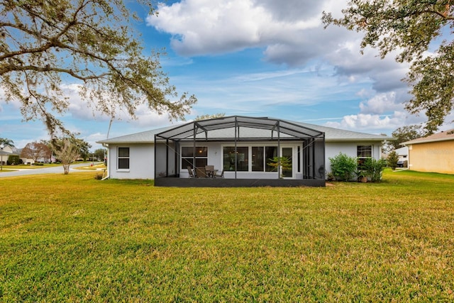 rear view of house with a lawn and a lanai