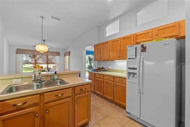 kitchen featuring visible vents, a sink, light countertops, vaulted ceiling, and white refrigerator with ice dispenser