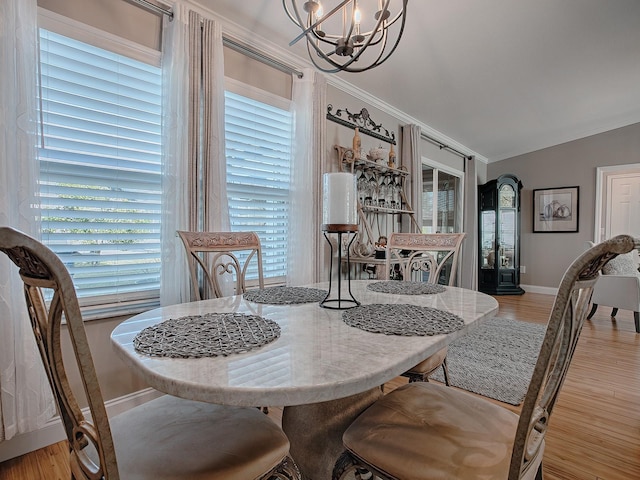 dining room with an inviting chandelier, ornamental molding, lofted ceiling, and light hardwood / wood-style flooring