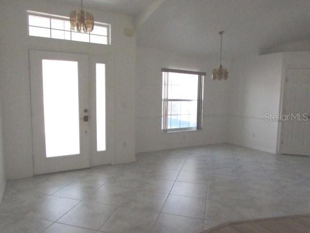 tiled foyer featuring a high ceiling, plenty of natural light, and an inviting chandelier