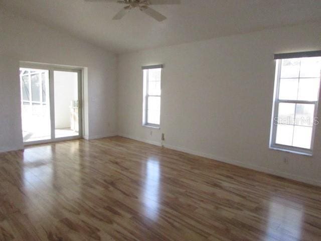 spare room with ceiling fan, wood-type flooring, and vaulted ceiling