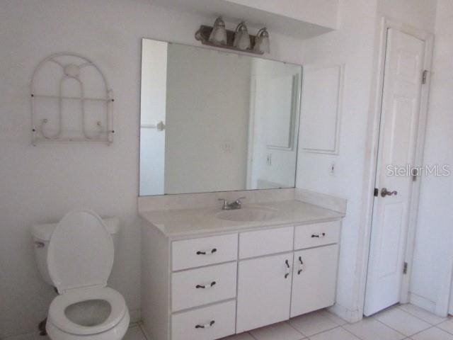 bathroom with toilet, vanity, and tile patterned flooring