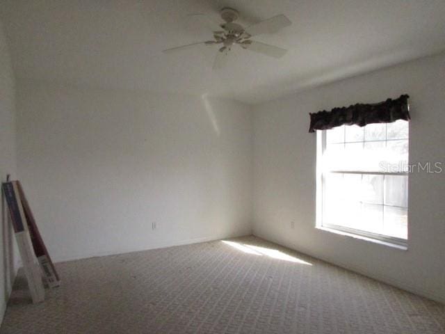 spare room featuring ceiling fan, a wealth of natural light, and carpet floors