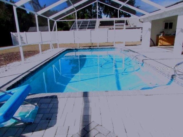 view of swimming pool featuring glass enclosure and a patio