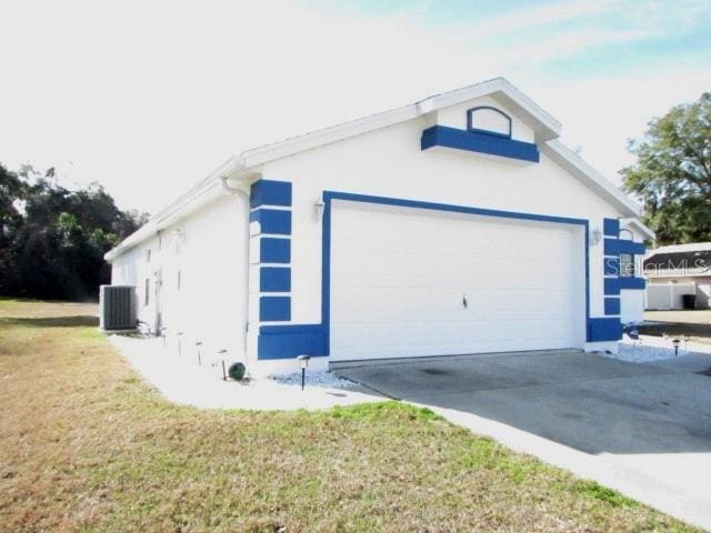 view of side of home with a garage, central air condition unit, and a lawn