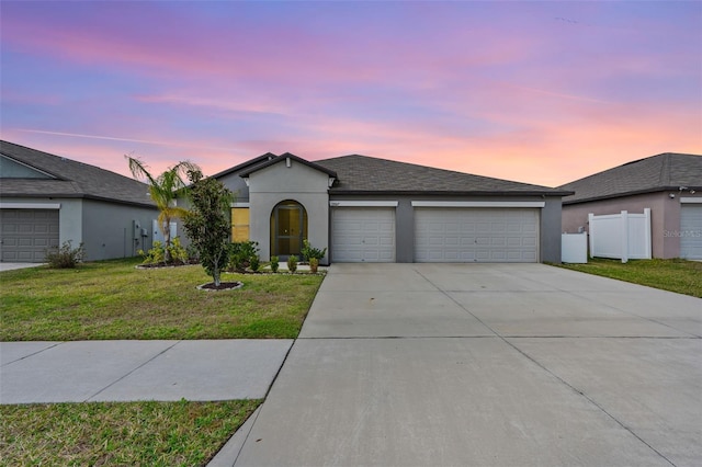 single story home featuring an attached garage, fence, concrete driveway, stucco siding, and a front yard