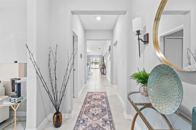 corridor featuring light tile patterned flooring and baseboards