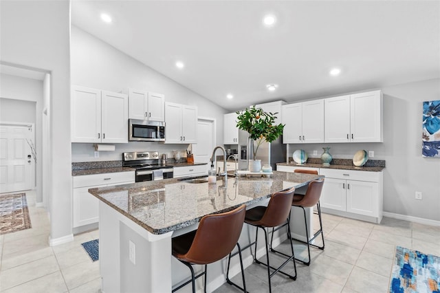 13557 Willow Bluestar Loop, Riverview, FL 33579 - kitchen featuring a breakfast bar, dark stone counters, a sink, an island with sink, and appliances with stainless steel finishes