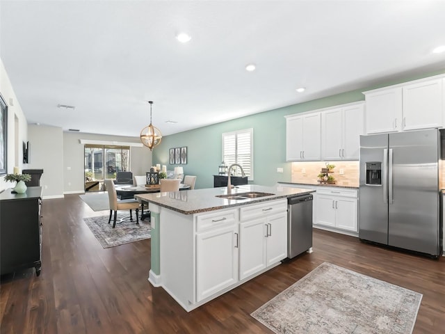 kitchen featuring an island with sink, white cabinetry, sink, dark stone countertops, and stainless steel appliances