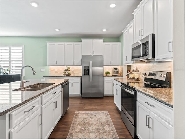 kitchen with dark wood-type flooring, sink, light stone counters, stainless steel appliances, and white cabinets