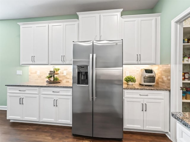 kitchen with stainless steel refrigerator with ice dispenser, dark stone counters, decorative backsplash, and white cabinets