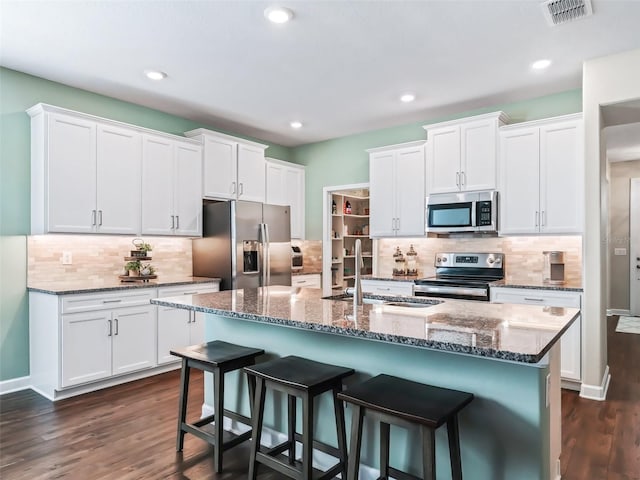 kitchen with stainless steel appliances, sink, a center island with sink, and white cabinets