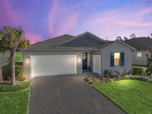 ranch-style home featuring a garage and a lawn