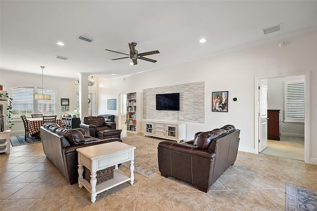 tiled living room with ceiling fan and crown molding