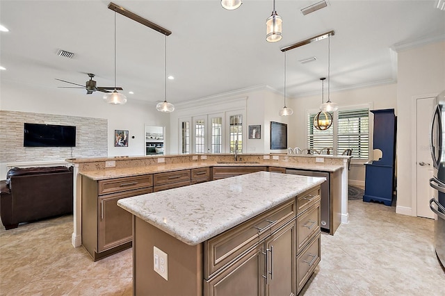 kitchen with ceiling fan, sink, hanging light fixtures, light stone countertops, and a large island