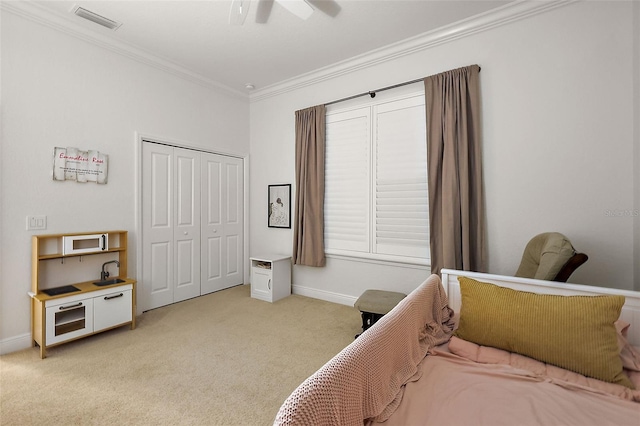 carpeted bedroom with ceiling fan, a closet, and crown molding