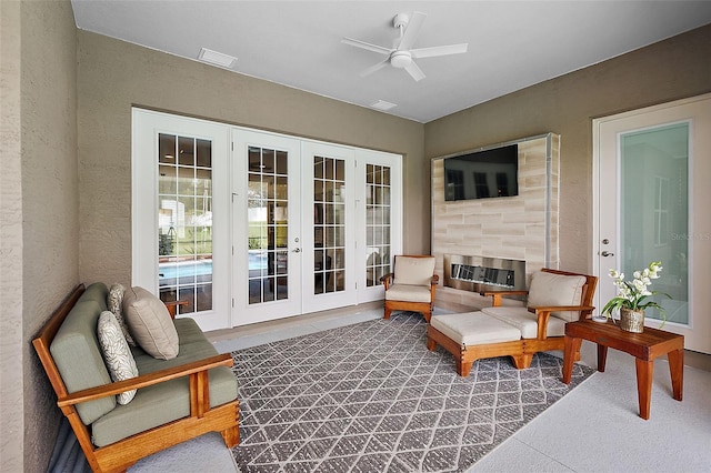 sunroom / solarium featuring ceiling fan, french doors, and a fireplace