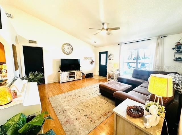 living room with ceiling fan, lofted ceiling, and light wood-type flooring