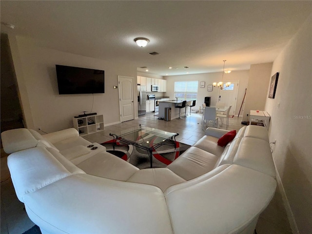 living area featuring light tile patterned floors, baseboards, visible vents, and an inviting chandelier