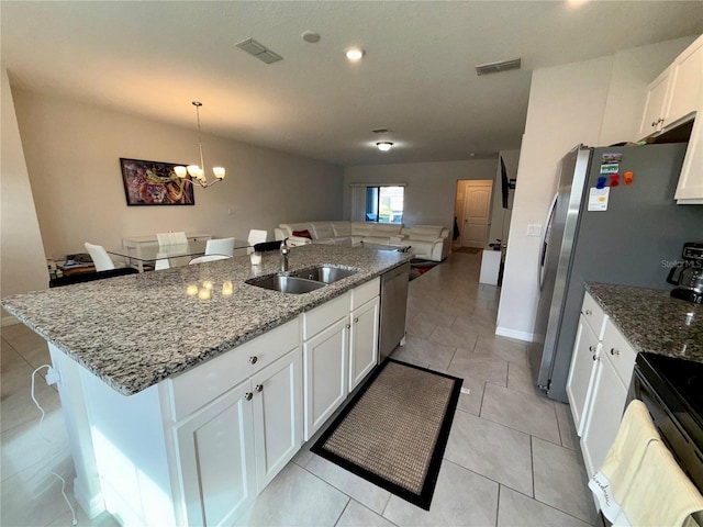 kitchen featuring stainless steel appliances, white cabinetry, a sink, and a center island with sink