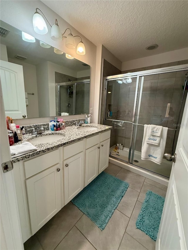 bathroom featuring tile patterned floors, vanity, a shower with shower door, and a textured ceiling