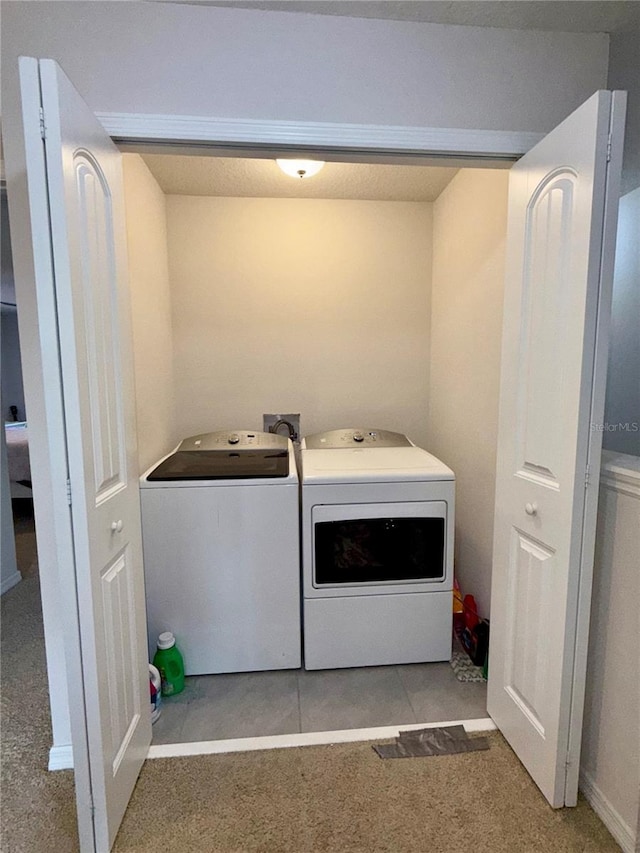 clothes washing area with washing machine and clothes dryer and light colored carpet