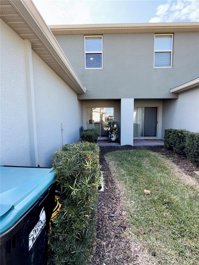 back of house with a yard and stucco siding