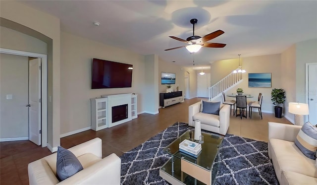 living room with ceiling fan with notable chandelier and a fireplace