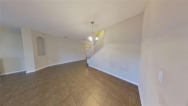 spare room with a notable chandelier and dark tile patterned flooring