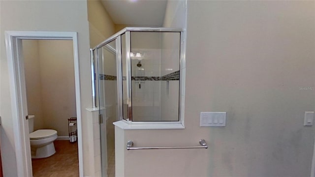 bathroom featuring toilet, tile patterned floors, and a shower with shower door