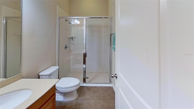 bathroom featuring vanity, toilet, an enclosed shower, and tile patterned flooring