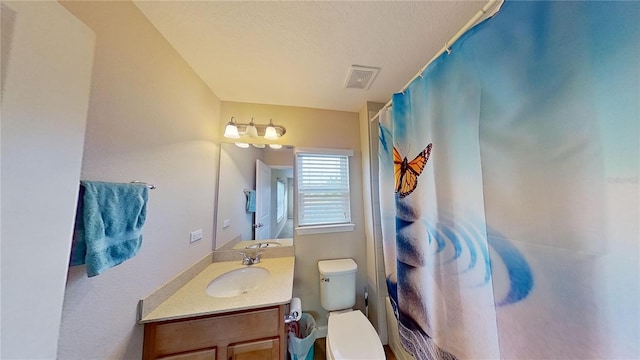 bathroom featuring toilet, walk in shower, and vanity