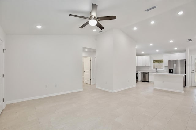 unfurnished living room with vaulted ceiling, ceiling fan, and sink