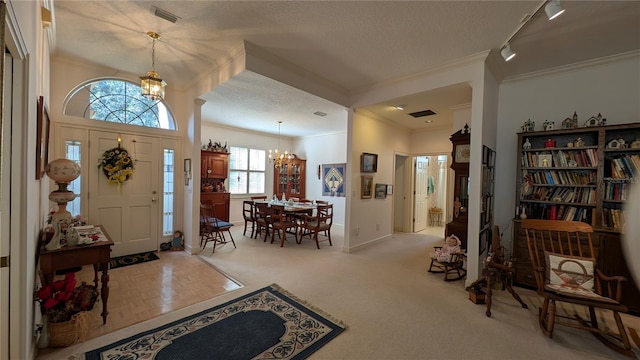 entryway featuring track lighting, a chandelier, ornamental molding, and a textured ceiling