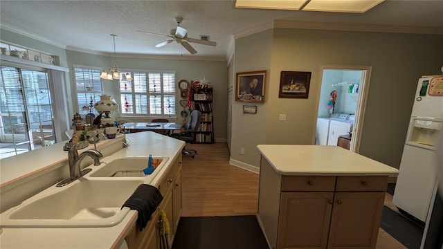 kitchen featuring a textured ceiling, white refrigerator with ice dispenser, sink, a center island with sink, and independent washer and dryer