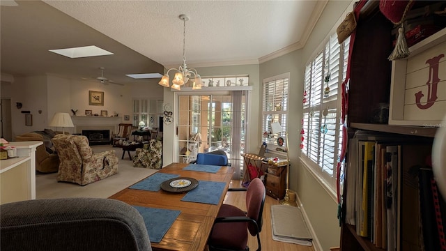 dining room with a skylight, ceiling fan with notable chandelier, crown molding, and a textured ceiling